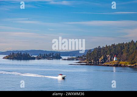 Hors-bord passant devant le phare de Portlock point sur l'île Prevost en Colombie-Britannique au Canada Banque D'Images