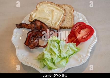 Séparez les ingrédients d'un sandwich bacon, laitue et tomate sur une assiette blanche avec du pain et de la mayonnaise. Banque D'Images