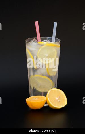 Limonade rafraîchissante dans un grand verre à facettes avec des tubes de glace et des tranches de citron mûres. Disposition verticale. Banque D'Images