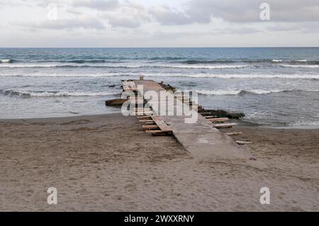 Passerelle en bois mène à la mer mouvante sous un ciel nuageux sur une plage de sable, Diana Marina, Ligurie, Italie Banque D'Images