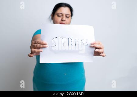 Femme indienne grasse en surpoids tenant le stress écrit du papier blanc. isolé sur fond blanc. Taille plus femelle. Banque D'Images
