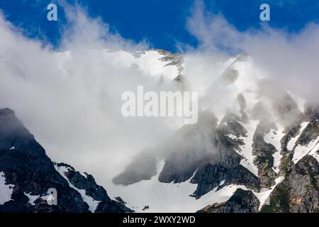 Nuages au-dessus de sommets montagneux hauts, dentelés et enneigés Banque D'Images