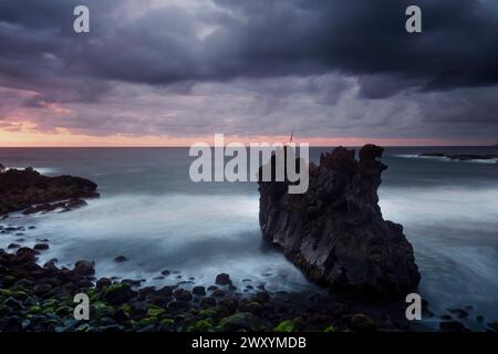 Les nuages Moody planent au-dessus de Playa del Bollullo alors que la première lumière de l'aube se lève, illuminant la spectaculaire roche volcanique et la mer brumeuse Banque D'Images