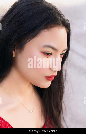 Portrait en gros plan d'une jeune femme regardant vers le bas, capturé dans un éclairage naturel doux, mettant en évidence ses traits et sa beauté culturelle Banque D'Images