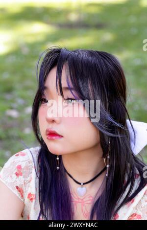 « Gros plan d'une jeune femme chinoise asiatique réfléchie avec une expression sereine, sur fond vert et doux. » Banque D'Images