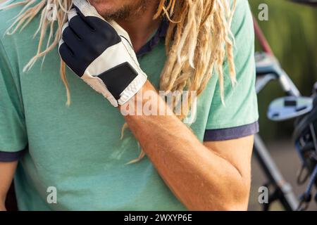 Gros plan recadré méconnaissable d'un golfeur distinctif avec des dreadlocks blonds ajustant leur gant, ajoutant un style non conventionnel à la traditiona Banque D'Images