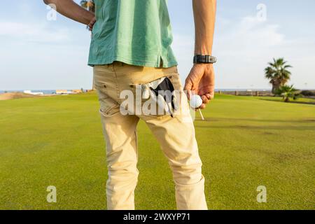 Un golfeur recadré méconnaissable avec des dreadlocks se tient sur un parcours verdoyant, prêt pour une session de golf unique. Banque D'Images