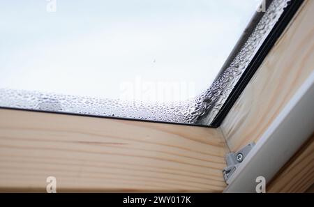 Gros plan de la condensation sur la fenêtre velux dans une maison, des gouttes d'eau et de l'humidité élevée Banque D'Images