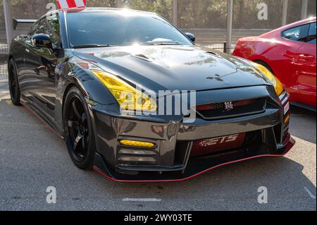 Vue avant d'une Nissan GT-R35 noire avec un kit de carrosserie en fibre de carbone lors d'une rencontre de voitures de sport japonaises. Banque D'Images