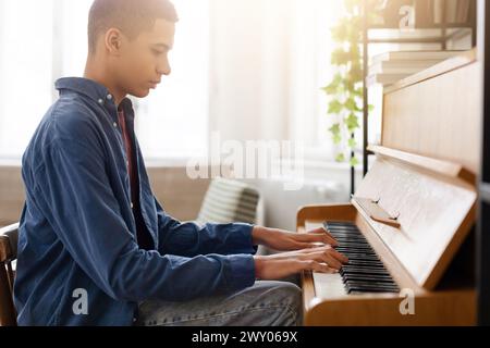 Jeune homme jouant du piano dans une pièce lumineuse Banque D'Images