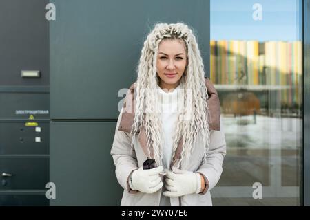 Femme avec de longs cheveux blonds portant un manteau blanc Banque D'Images