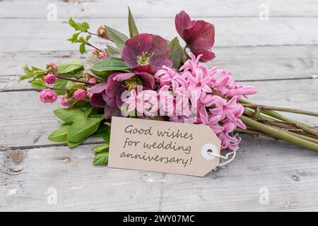 Bouquet avec jacinthes roses, roses de Noël et carte avec texte anglais : bons voeux pour anniversaire de mariage Banque D'Images