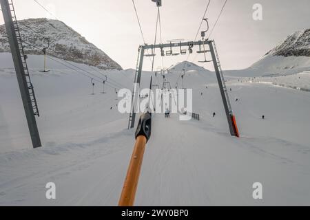 Levage sur la corde de téléski au-dessus de la lumière du soleil près du sommet de la montagne, vue d'un skieur Banque D'Images