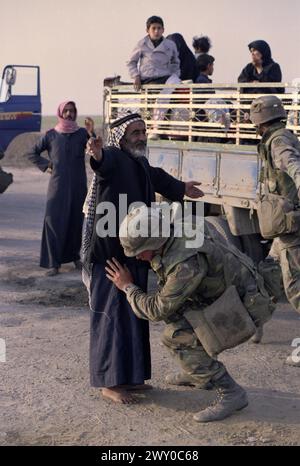 Première Guerre du Golfe : 26 mars 1991 Un soldat de l'armée américaine fouille un vieil homme au dernier poste de contrôle américain, à seulement 8 km au sud de Nasiriyah dans le sud de l'Irak. Banque D'Images