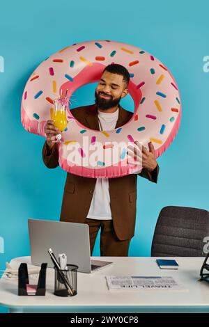 Un homme tient de manière ludique un beignet géant devant son visage, créant une scène fantaisiste et humoristique. Banque D'Images