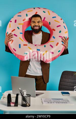 Un homme tient de manière ludique un beignet géant devant son visage, jetant un coup d'œil à travers le trou avec un sourire espiègle. Banque D'Images