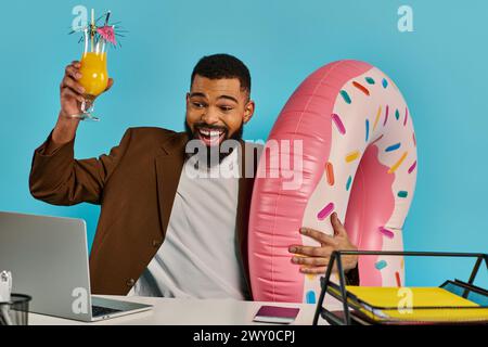 Un homme avec une expression réfléchie est assis à un bureau, tenant un verre de jus d'orange rafraîchissant. Banque D'Images