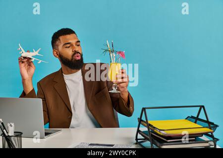 Un homme est assis à un bureau, verre de jus d'orange à la main, profondément dans la pensée. La douce lueur de la lumière du matin remplit la pièce. Banque D'Images