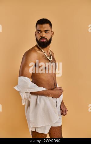 Un homme serein avec une barbe luxuriante orne gracieusement une serviette blanche croustillante, dégageant un sentiment de calme et de détente. Banque D'Images