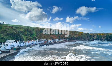 Pennan Village Aberdeenshire Écosse ciel bleu sur les maisons et la mer avec pulvérisation sur le brise-lames à marée haute Banque D'Images