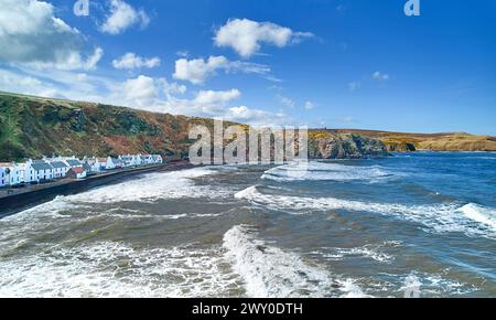 Pennan Village Aberdeenshire Écosse ciel bleu au-dessus des maisons et des vagues à marée haute Banque D'Images