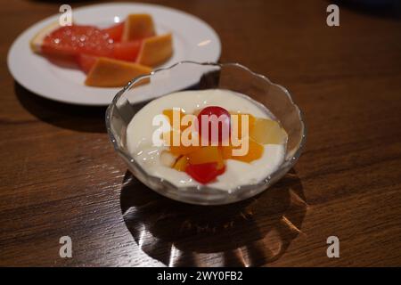 Yaourt avec des fruits dans un bol en verre sur une table en bois Banque D'Images