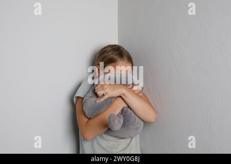 Jeune fille pleurant avec les mains et jouet couvrant le visage à la maison Banque D'Images