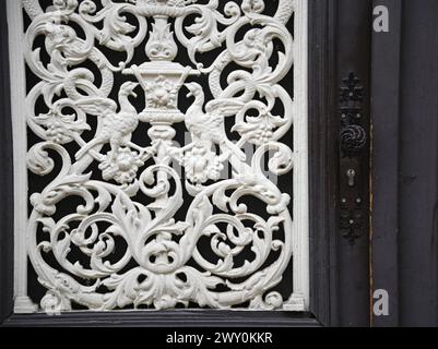 Grilles anciennes en fonte à travail ouvert sur une porte d'entrée en bois vintage à Obernai, Alsace France. Banque D'Images