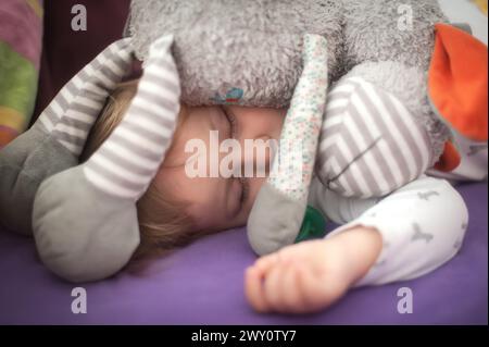 Mignon bébé garçon dort paisiblement avec une sucette, tenant son jouet en peluche préféré, sous la lumière du jour douce. Incarnation tranquillité et innocence Banque D'Images