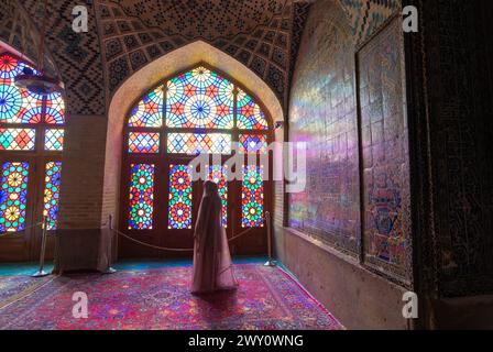 Shiraz, Iran - 29 février 2024 : la mosquée Nasir al-Mulk, également connue sous le nom de mosquée rose, Une femme locale se tient devant le vitrail coloré Banque D'Images