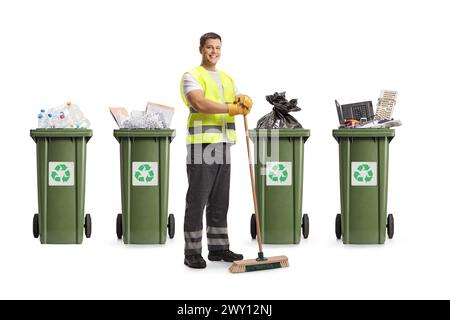 Nettoyant dans un uniforme tenant un balai devant des bacs de recyclage isolés sur fond blanc Banque D'Images