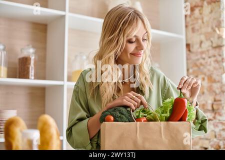 Femme tient le sac en papier plein de légumes frais dans la cuisine à la maison. Banque D'Images