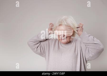 Femme senior avec masque de sommeil sur studio Banque D'Images