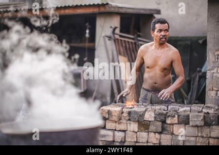 Ambatolampy, Madagascar - 25 avril 2019: Usine de traitement de l'aluminium, les boîtes sont fondues dans des pots avec de l'eau bouillante sur le feu à l'extérieur, la vapeur abov Banque D'Images