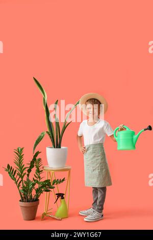 Mignon petit jardinier avec arrosoir et plantes sur fond orange Banque D'Images