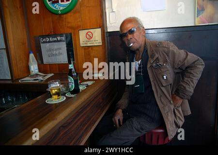 Homme de couleur au bar homme adulte mature avec ethnie africaine assis dans un bar sur Nieuwe Binnenweg, fumant une Cigrarette et buvant un verre de bière Heineken. Rotterdam Cafe, Nieuwe Binnenweg Zuid-Holland Nederland Copyright : xGuidoxKoppesx Banque D'Images