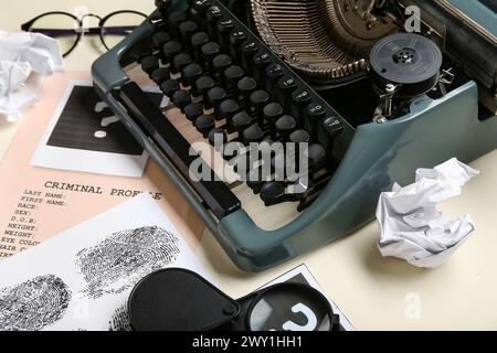 Machine à écrire rétro, dossiers criminels et boules de papier froissées sur fond clair, gros plan Banque D'Images