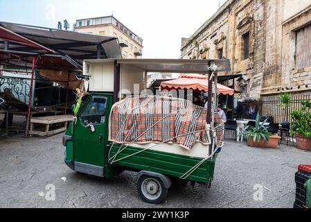 Palerme, Italie - 13 mai 2023 : Piaggio tricycle garé dans le marché Ballaro, marché de nourriture de rue avec des gens autour de Palerme, Sicile, Italie Banque D'Images