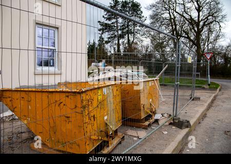 Deux bennes à ordures jaunes sur un nouveau site de construction de logements une benne est pleine de plaques de plâtre coupées avec une clôture de sécurité autour du site. Banque D'Images