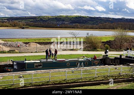 L'eau dans le réservoir de Barrowford brille dans le soleil du printemps East Lancashire le vendredi Saint alors qu'un bateau étroit monte à travers une écluse Banque D'Images