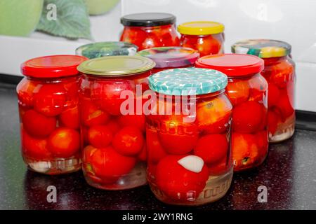 Bocaux en verre avec tomates rouges remplies de saumure. Préparations pour l'hiver, conserves de tomates. Banque D'Images