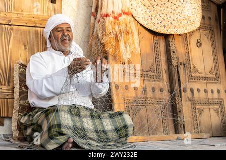 Le vieil homme tisse une cage de pêche traditionnelle en métal dans les célébrations Darb Al Saai de la fête nationale du Qatar. Banque D'Images