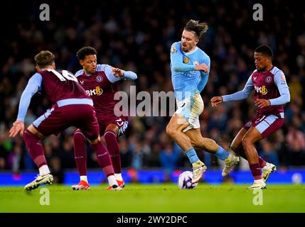 Jack Grealish de Manchester City (au centre) et Leon Bailey d'Aston Villa (à droite) s'affrontent pour le ballon lors du match de premier League à l'Etihad Stadium de Manchester. Date de la photo : mercredi 3 avril 2024. Banque D'Images