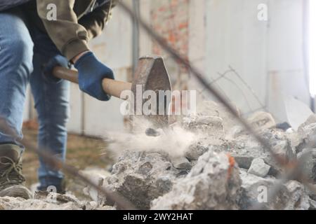 Homme brisant des pierres avec un marteau de forge à l'extérieur, gros plan Banque D'Images