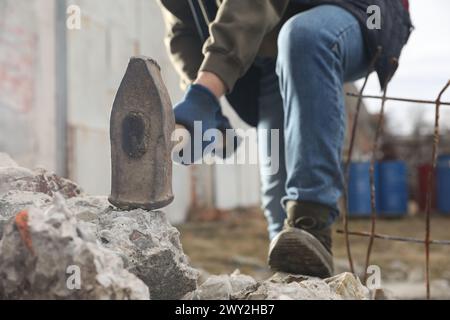 Homme brisant des pierres avec un marteau de forge à l'extérieur, gros plan Banque D'Images