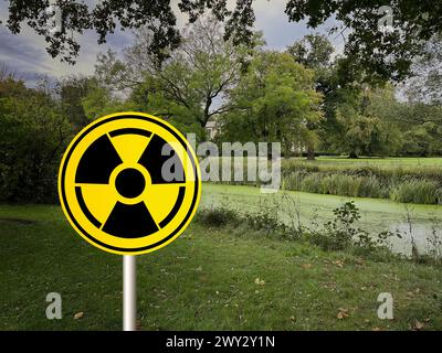 Pollution radioactive. Panneau d'avertissement jaune avec symbole de danger dans les zones rurales Banque D'Images