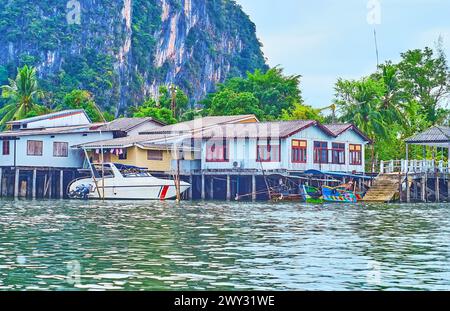 Les vieilles cabanes denses sur pilotis le long du rivage contre les arbres tropiques et la roche, Phang Nga Bay, Thaïlande Banque D'Images