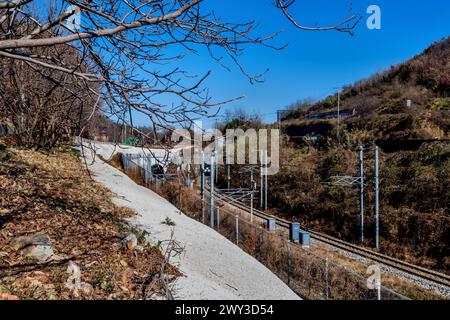 Voies ferrées et lignes électriques avec des lumières sur la locomotive vues dans le tunnel avant de sortir du tunnel en Corée du Sud Banque D'Images