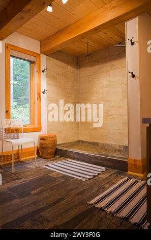 Cabine de douche illuminée en céramique beige dans la salle de bains principale, carrelage en céramique brun et gris foncé et tapis rayés bleus et blancs au rez-de-chaussée Banque D'Images