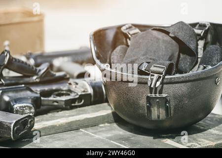 La machine, la mitrailleuse, le casque de l'armée avec une lampe de poche couchée dans une pile sur une boîte en bois de munitions. Mener des opérations militaires. Banque D'Images